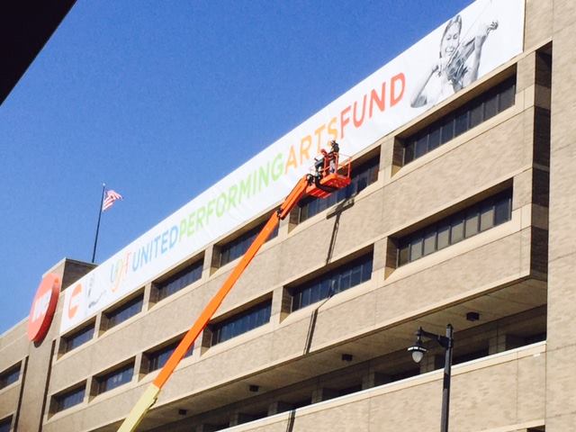 Construction workers put up a enormous UPAF banner on WE energies building 