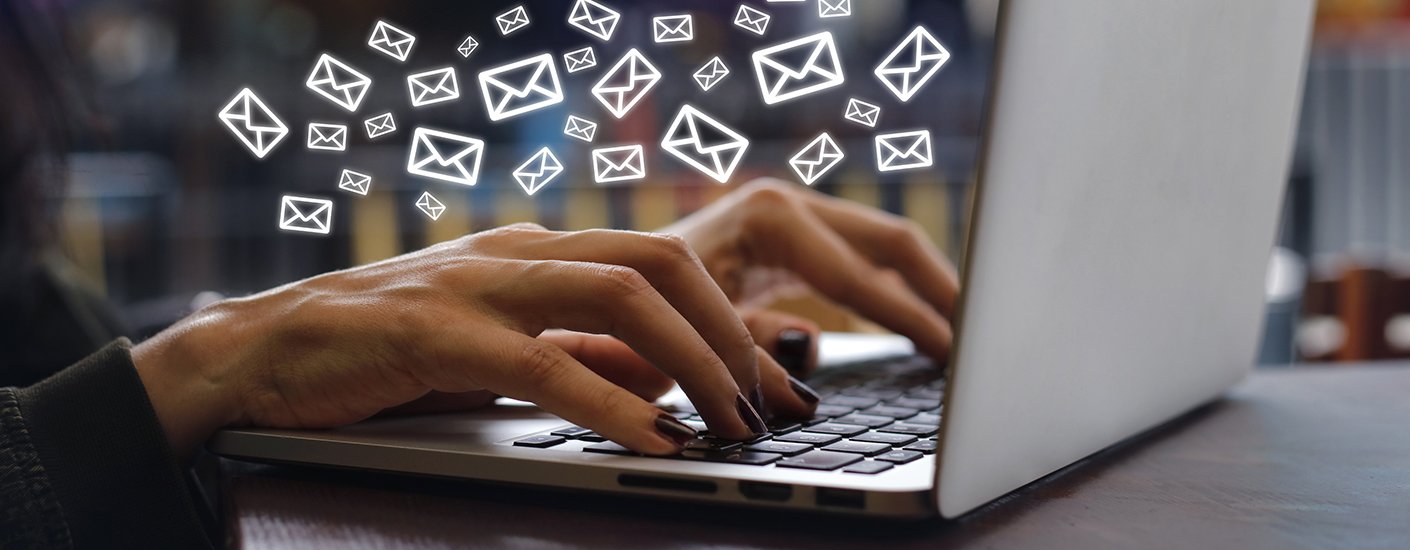 woman typing on laptop with email icons surrounding her hands